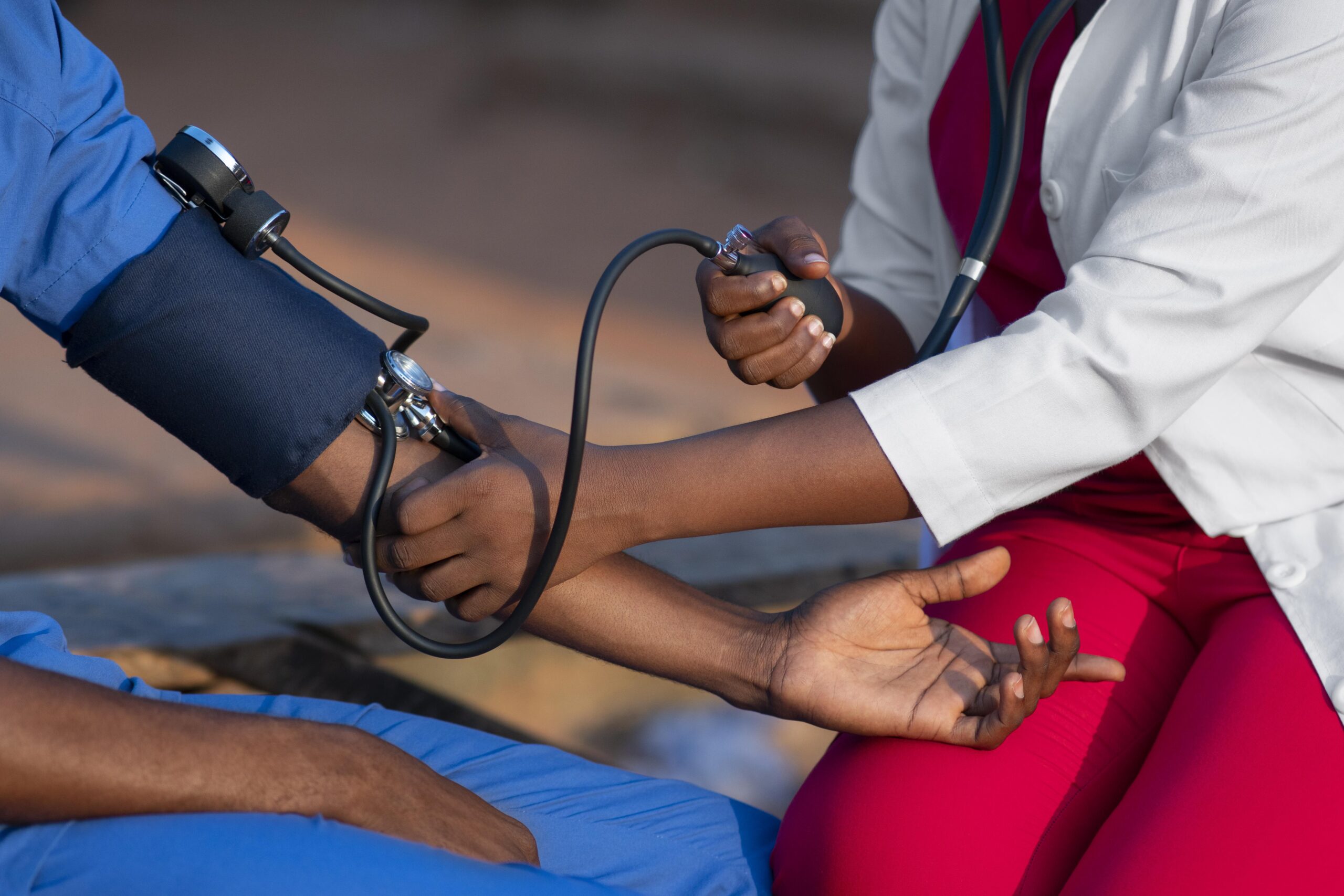 La main d'un médecin prends la tension d'une personne dont on voit le bras.